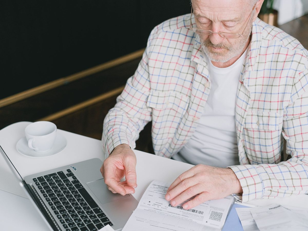 Investor reviewing account statements at a desk next to a laptop