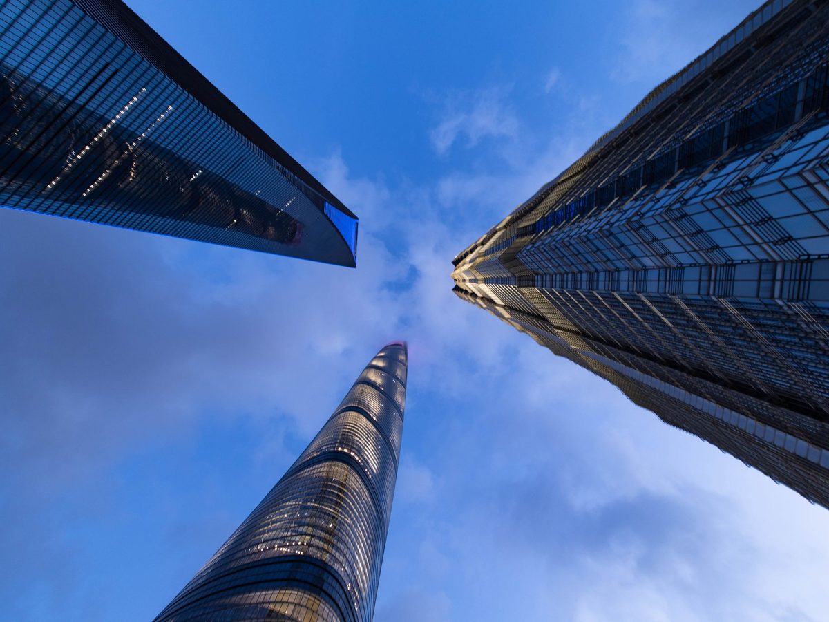 Glass office towers seen from street level against a blue sky